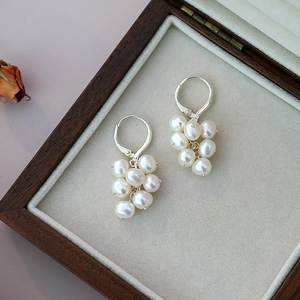 Detailed close-up of natural freshwater pearl cluster earrings on a vintage jewelry box