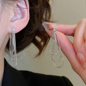 Gros plan détaillé montrant la texture des boucles d'oreilles à pompons en argent et chaînes
