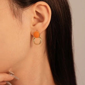 Detail of vintage geometric earrings with orange enamel and interlocking golden rings