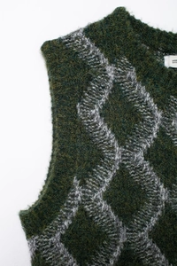 Gros plan détaillé du gilet en tricot vert foncé avec motif de losanges gris en laine
