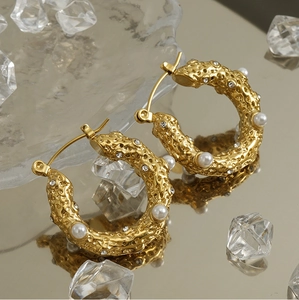 Detail of 18k gold plated hoop earrings with lava texture, white pearls and sparkling crystals