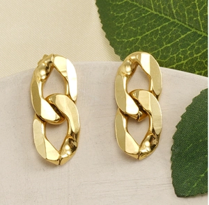 Détail de boucles d'oreilles en maille dorée 18 carats sur un socle en pierre grise