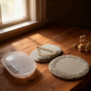 Detail of vintage flower relief resin plate molds and jewelry display tray on wood