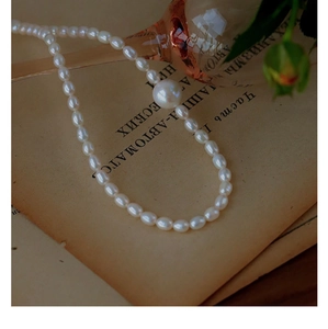 Detail of freshwater rice pearl necklace with a central large round pearl on vintage pages