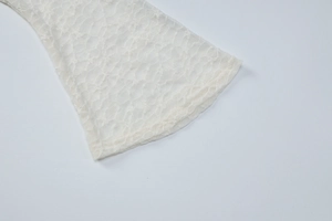 Détail de la manche en dentelle blanche avec motifs floraux et poignets évasés