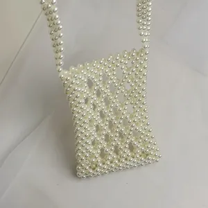 Detail of handmade pearl beaded crossbody bag with hollow lattice design and long strap