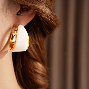 Close-up of model wearing gold plated round resin pendant hoop earrings in retro style