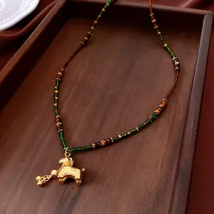 Tiger eye glass bead necklace with golden pony pendant on vintage silk tray
