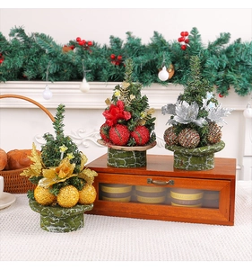 Close-up of mini Christmas trees with gold, red and silver ornaments on a cozy wooden desk