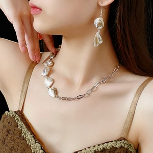 Parure collier et boucles d'oreilles en perles baroques portée avec détails argentés