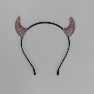 Macro detail of pink glitter devil horns on a black festive headband for parties