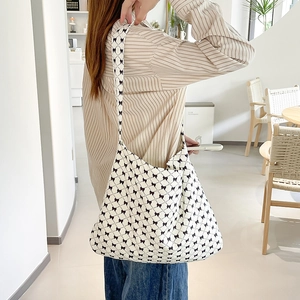 Close-up of white canvas shoulder bag with black bow print on a lifestyle model