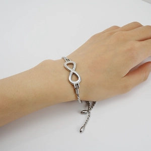 Macro detail of silver infinity symbol bracelet featuring an adjustable rope chain design