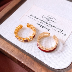 Detailed close-up of gold-plated double-layer chain rings with red enamel and heart gems