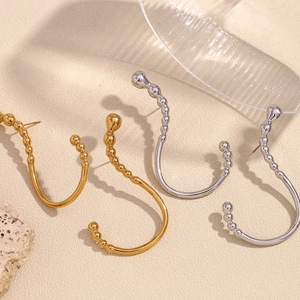 Detail of creative question mark earrings in gold and silver finish on textured background