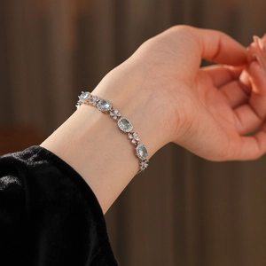 Macro detail of silver floral bracelet with light blue zircon and oval gemstones