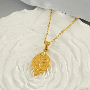 Close-up of golden leaf pendant with coin pattern on white rose stone base