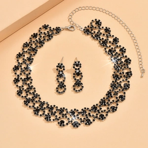 Detailed view of silver necklace and drop earrings set with shimmering black rhinestones