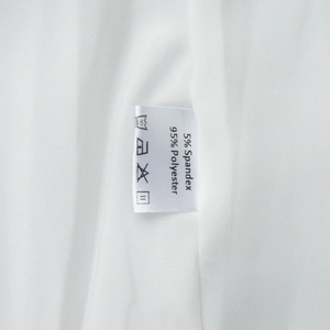 Détail de l'étiquette d'entretien d'une robe blanche en 95% polyester et 5% élasthanne