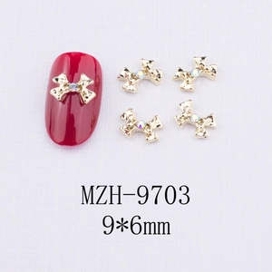 Détail d'un bijou d'ongle en alliage doré 9x6mm avec strass sur un faux ongle rouge