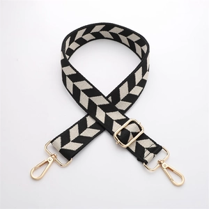 Detail of adjustable black and white houndstooth canvas bag strap with gold metal buckles