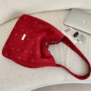 Dettaglio della borsa shopper in lana rossa con stelle argentate e logo dorato