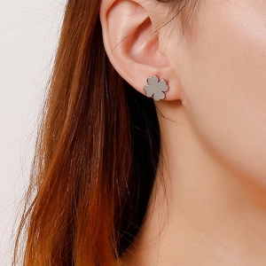 Gros plan de boucles d'oreilles trèfle à quatre feuilles en argent portées par un modèle