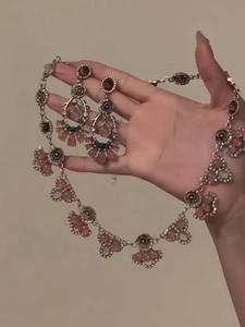Close-up of pink resin flower pendant necklace and earrings set held in hand
