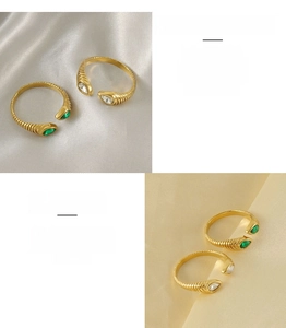 Detail of gold spiral stainless steel ring with water drop green and white zircons