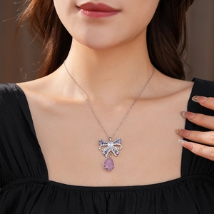 Close-up of bow necklace pendant with purple teardrop gemstone and sparkling zircon crystals