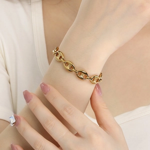 Macro detail of polished gold pig nose chain bracelet worn on a female wrist
