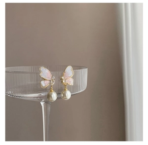 Detail of gradient butterfly earring with pearl drop on a striped glass edge