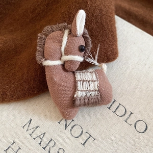 Macro shot of handcrafted fabric horse brooch featuring embroidery on vintage book pages