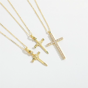 Three vintage gold necklaces featuring cross and sword snake pendants with green gems
