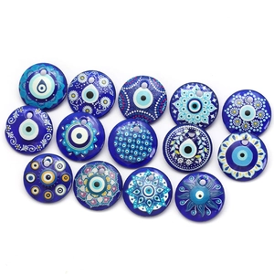 Flat lay macro of 14 blue evil eye glass charms featuring unique hand-painted details