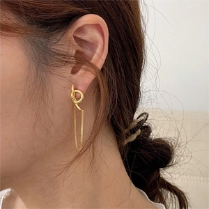Detail view of gold-plated knot ring earrings with long metal chain tassels