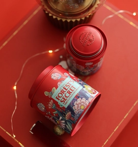 Detailed view of red tin canisters with floral patterns and debossed metal brand logos