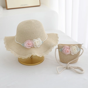 Detailed view of beige straw hat and bag set with pink silk flowers and lace trim