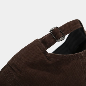 Close-up of dark brown baseball cap featuring adjustable metal buckle and cotton texture