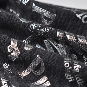 Detailed close-up of black knit fabric with metallic silver PINK letter printing
