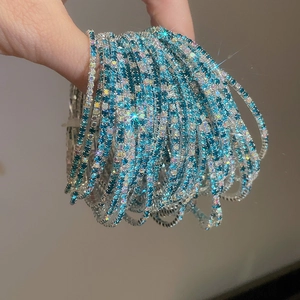 Close-up of stacked elastic bracelets with blue and iridescent crystals on silver bands