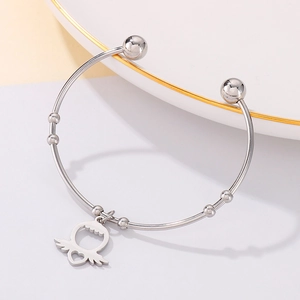 Detailed macro of silver-toned stainless steel cuff bracelet with heart wing charm