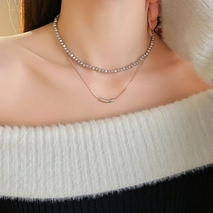 Close-up of double-layer silver beaded and snake chain necklace on model neck