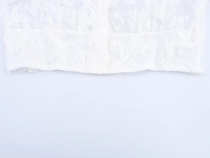 Close-up of white floral lace fabric with delicate embroidery and round buttons detail