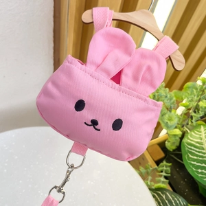 Arnés mochila rosa con forma de conejo para perro colgado en una percha de madera