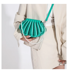 Detailed view of a green shell-shaped bag with a pearl chain and leather strap