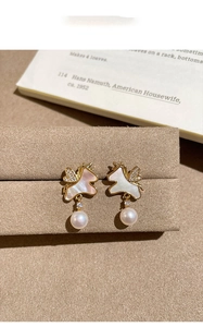 Détail macro d'une boucle d'oreille licorne dorée avec nacre, zircon et perle blanche