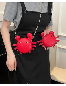 Detail showing the red crab-shaped shoulder bag and mini coin purse with gold chain strap