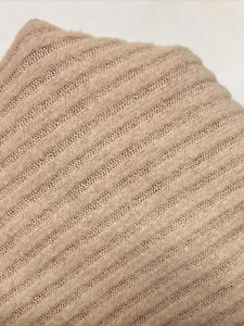 Macro shot of warm beige ribbed knit fabric showing thick wool-like texture and soft fibers