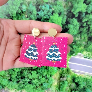 Pink acrylic Christmas tree earrings with festive holiday patterns and gold stud accents